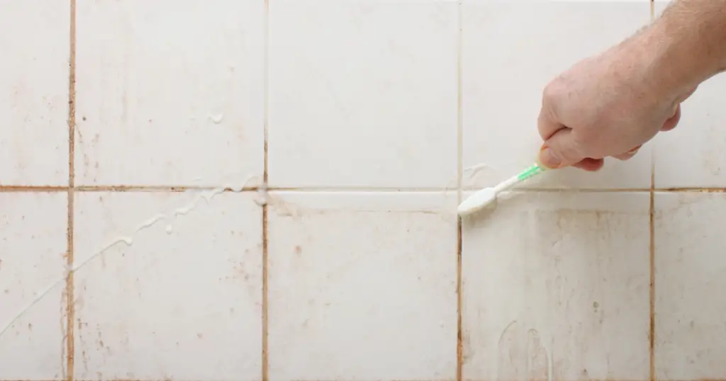 Using a toothbrush to clean grout line